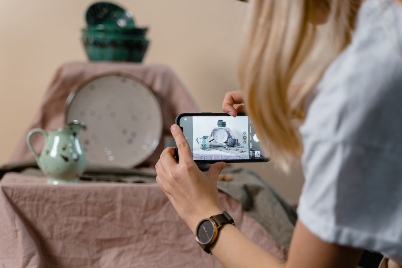 Mujer fotografiando con su celular unas piezas de cerámica para publicarlas